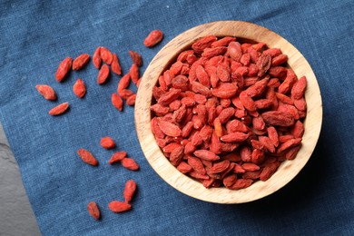 Dried goji berries on blue cloth, top view