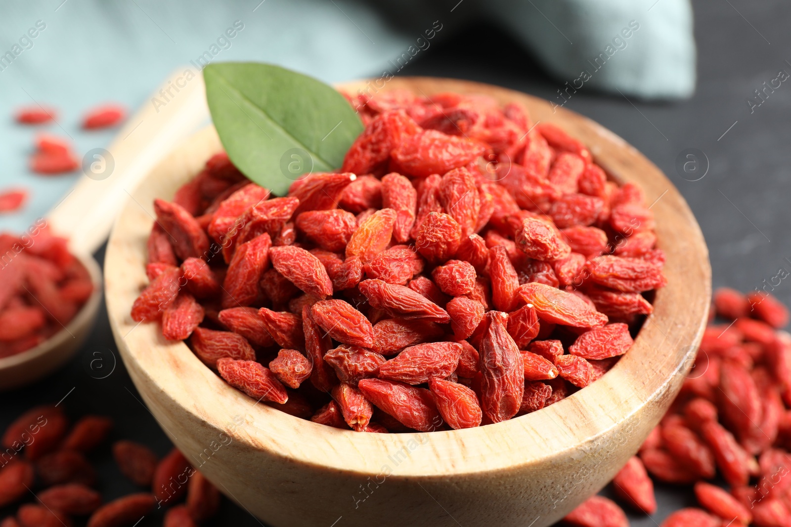 Photo of Dried goji berries in wooden bowl on table, closeup