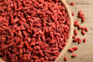 Dried goji berries in bowl on wooden table, top view