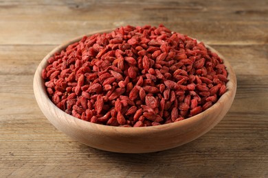 Photo of Dried goji berries in bowl on wooden table, closeup