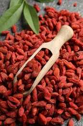 Photo of Dried goji berries and scoop on grey textured table, above view