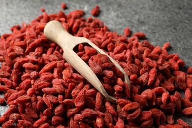 Dried goji berries and scoop on grey textured table, closeup