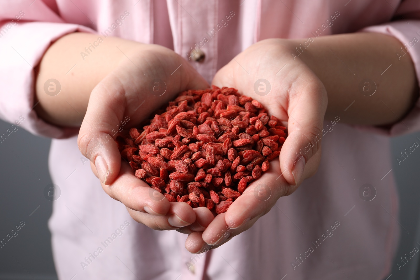 Photo of Woman holding pile of dried goji berries, closeup