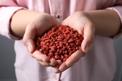 Woman holding pile of dried goji berries, closeup