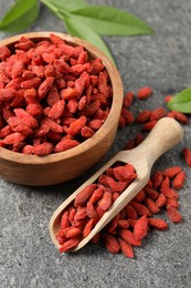 Dried goji berries and leaves on grey textured table