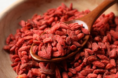 Dried goji berries and spoon in wooden bowl, closeup