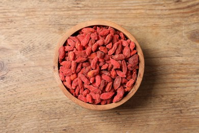 Photo of Dried goji berries in bowl on wooden table, top view