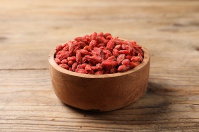 Dried goji berries in bowl on wooden table, closeup