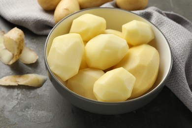 Fresh raw potatoes and peels on grey table