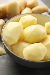 Fresh raw potatoes in bowl on grey table, closeup