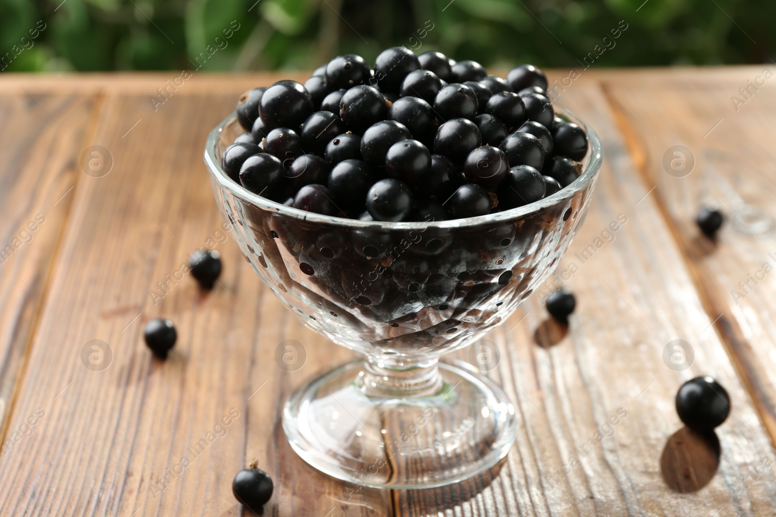 Photo of Ripe black currants in glass on wooden table