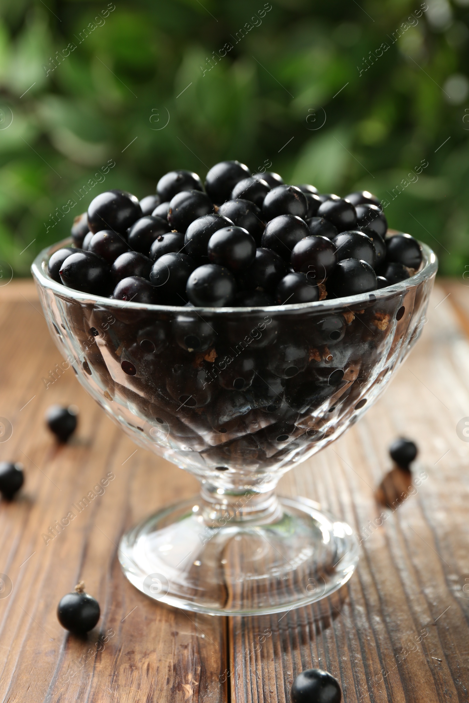 Photo of Ripe black currants in glass on wooden table