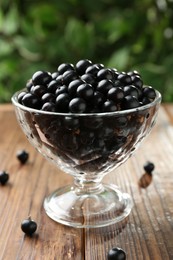 Ripe black currants in glass on wooden table