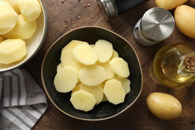 Photo of Fresh raw potatoes, spices and oil on wooden table, top view