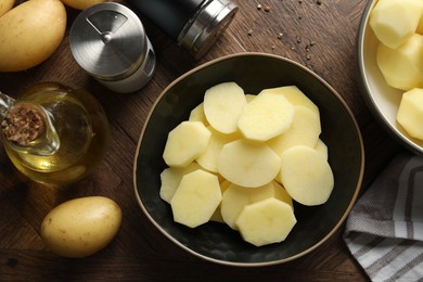 Photo of Fresh raw potatoes, spices and oil on wooden table, top view