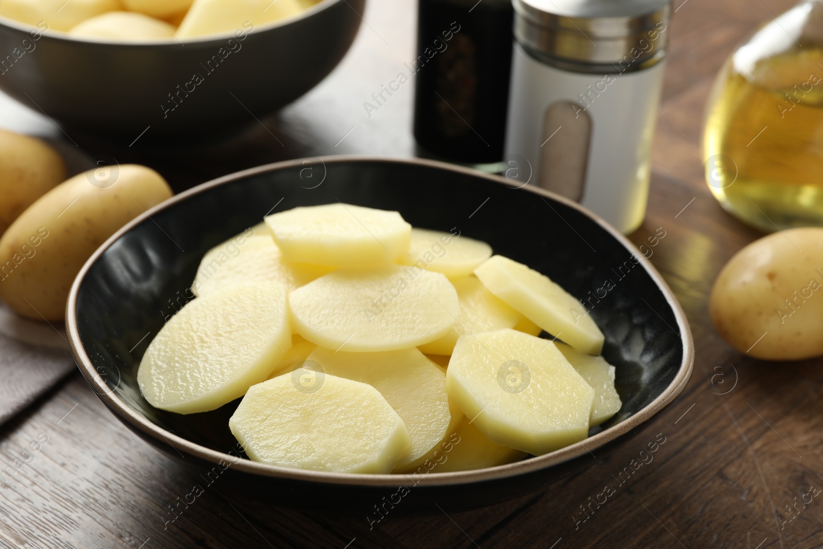 Photo of Whole and cut fresh raw potatoes on wooden table