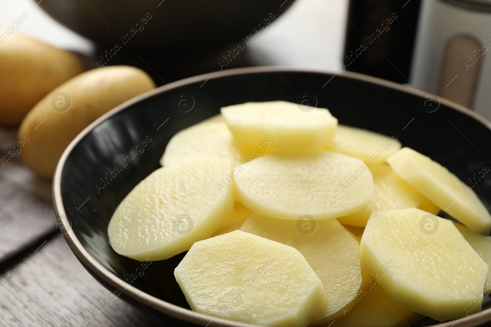 Photo of Cut fresh raw potatoes in bowl on table, closeup