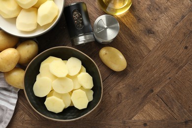 Photo of Fresh raw potatoes, spices and oil on wooden table, top view. Space for text