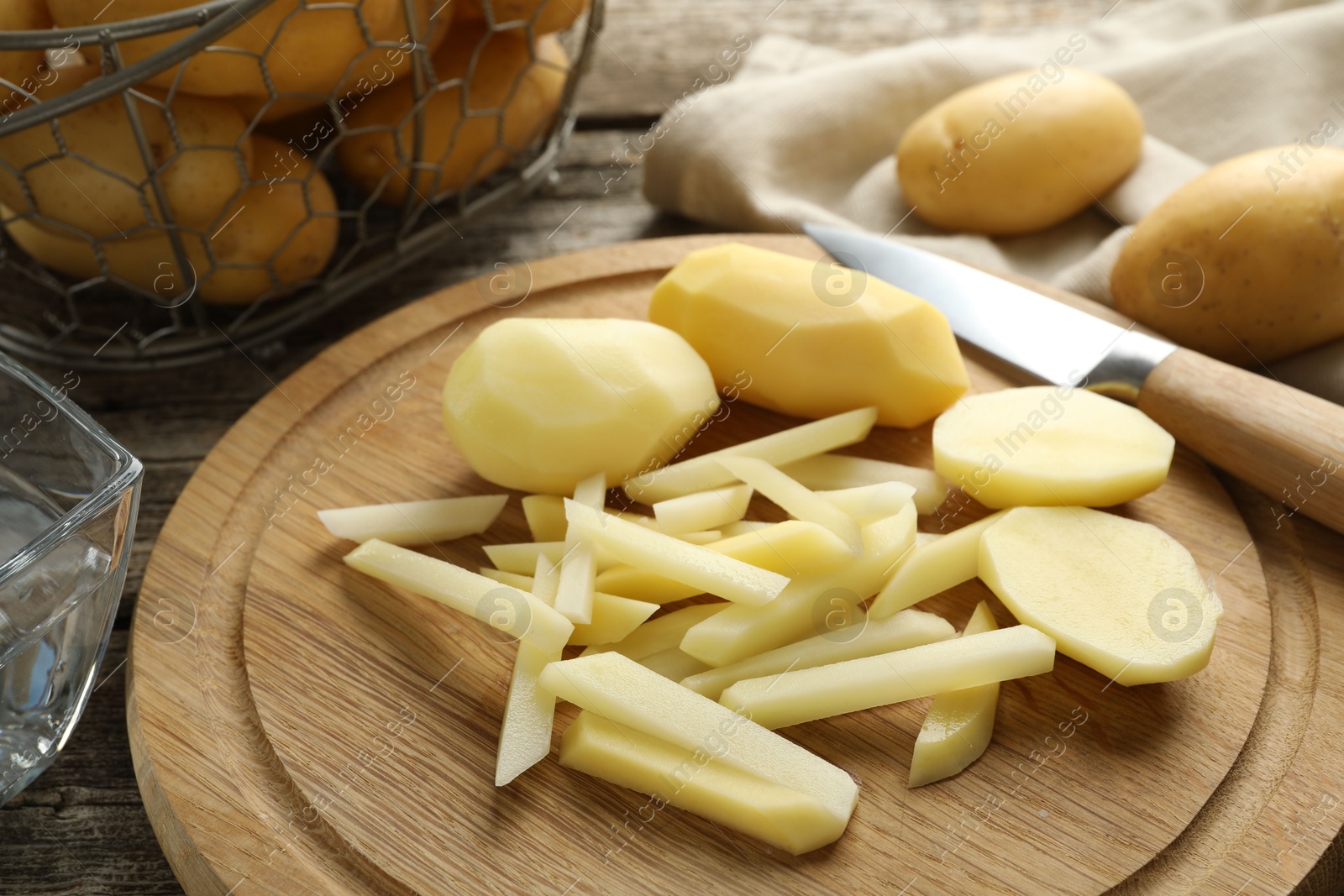 Photo of Whole and cut fresh raw potatoes near knife on wooden table