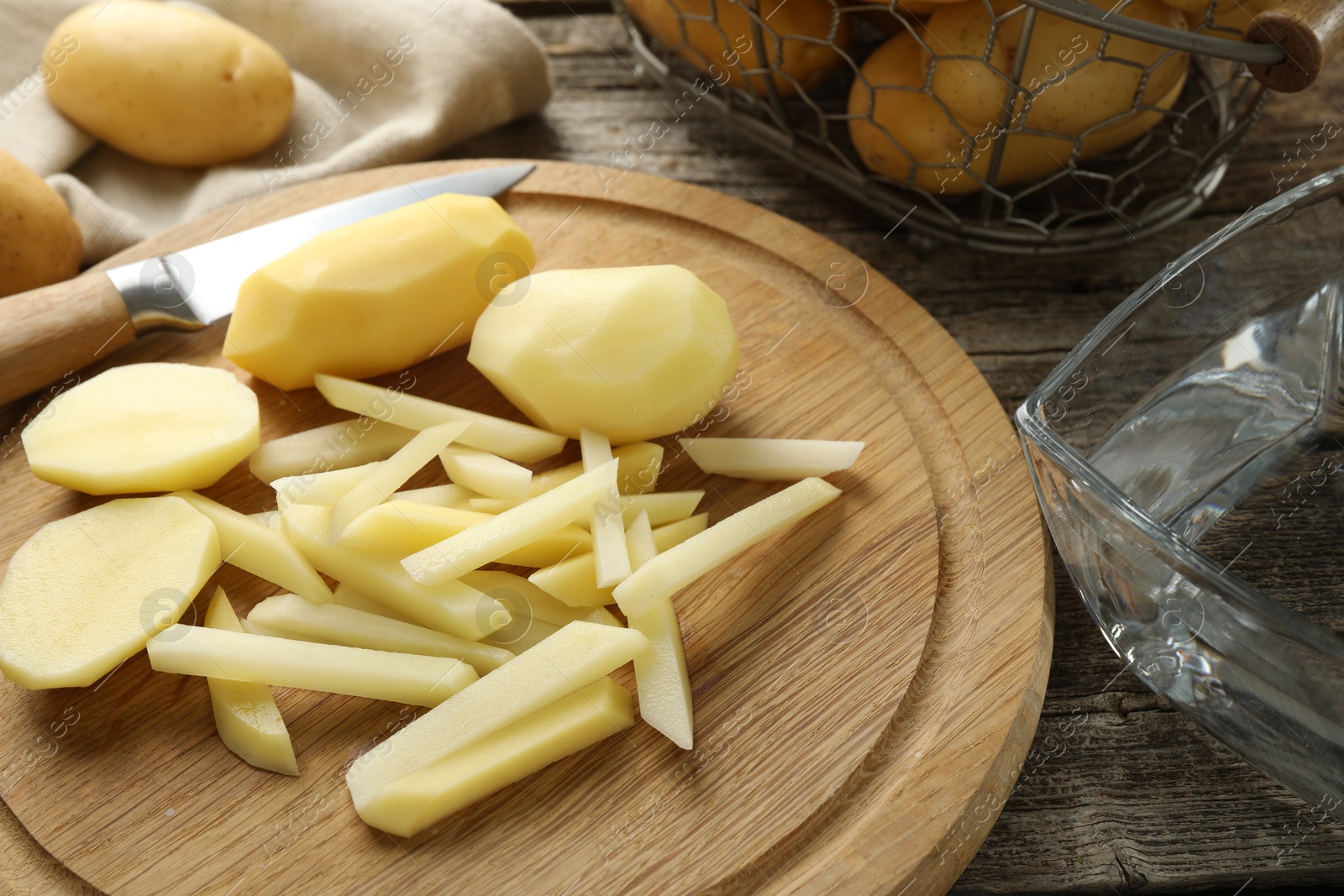 Photo of Whole and cut fresh raw potatoes near knife on wooden table