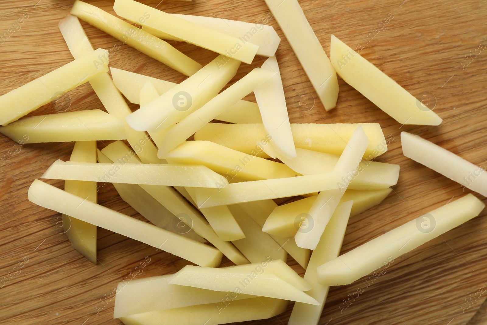 Photo of Cut fresh raw potatoes on wooden table, top view