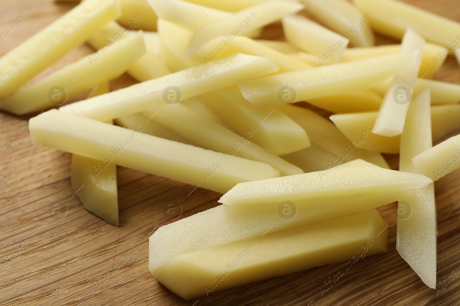 Photo of Cut fresh raw potatoes on wooden table, closeup