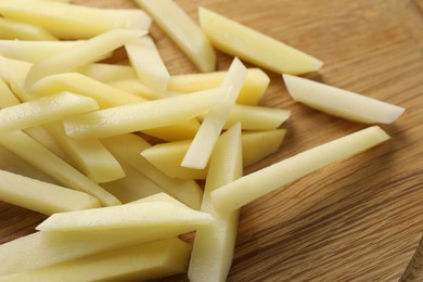 Photo of Cut fresh raw potatoes on wooden table, closeup