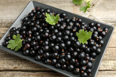 Photo of Ripe black currants and leaves on wooden table, closeup