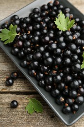 Ripe black currants and leaves on wooden table, above view