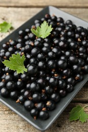 Ripe black currants and leaves on wooden table, closeup