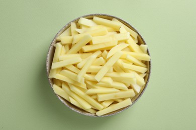 Fresh raw potatoes in bowl on green background, top view