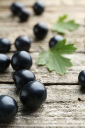 Ripe blackcurrants and green leaves on wooden table, closeup