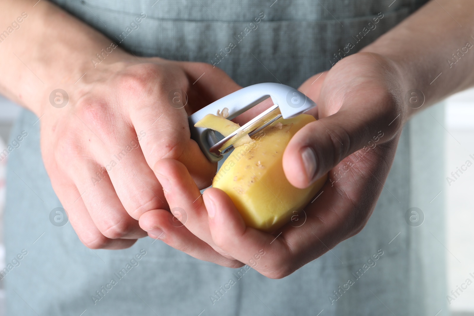 Photo of Man peeling fresh potato with peeler, closeup