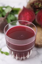 Fresh beet juice in glass and ripe vegetables on table, closeup