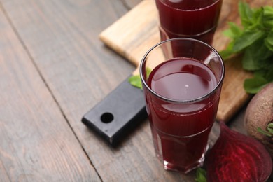 Photo of Fresh beet juice in glasses, ripe vegetables and mint on wooden table, closeup. Space for text