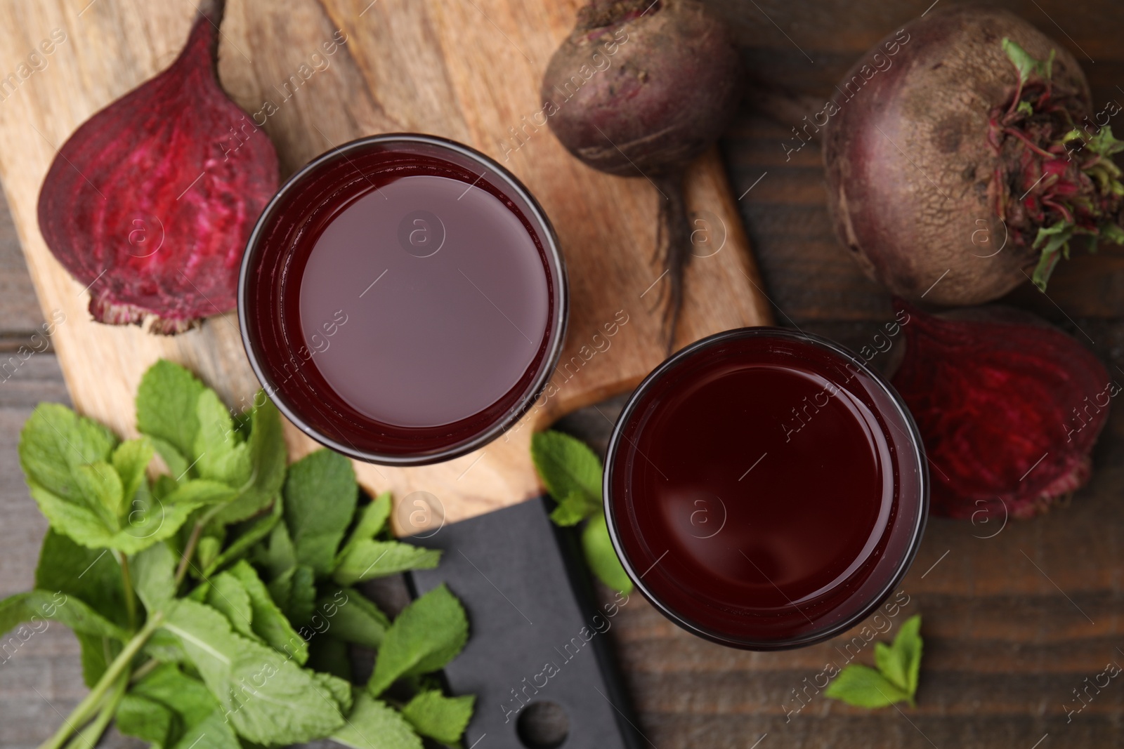 Photo of Fresh beet juice in glasses, ripe vegetables and mint on wooden table, flat lay