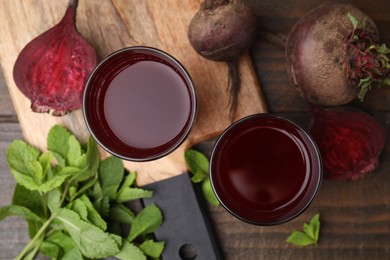 Photo of Fresh beet juice in glasses, ripe vegetables and mint on wooden table, flat lay