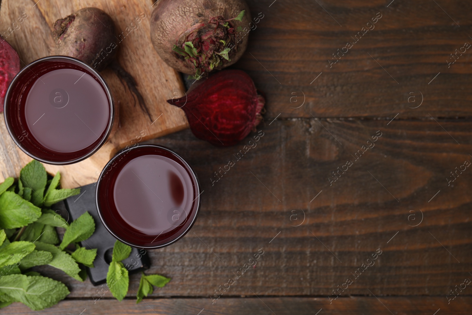 Photo of Fresh beet juice in glasses, ripe vegetables and mint on wooden table, flat lay. Space for text