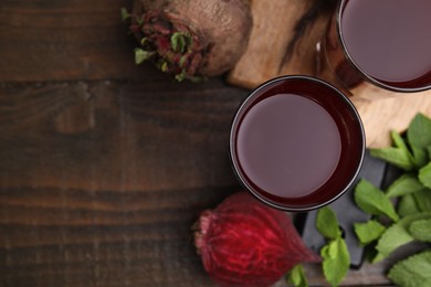 Fresh beet juice in glasses, ripe vegetables and mint on wooden table, flat lay. Space for text