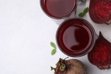 Fresh beet juice in glass and ripe vegetables on white table, flat lay. Space for text