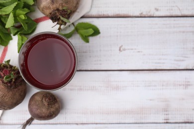 Fresh beet juice in glass, ripe vegetables and mint on white wooden table, flat lay. Space for text