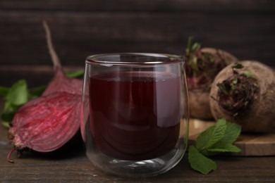 Photo of Fresh beet juice in glass, ripe vegetables and mint on wooden table, closeup