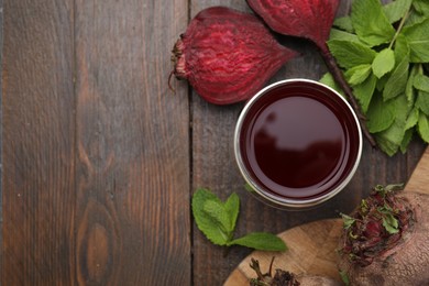 Fresh beet juice in glass, ripe vegetables and mint on wooden table, flat lay. Space for text