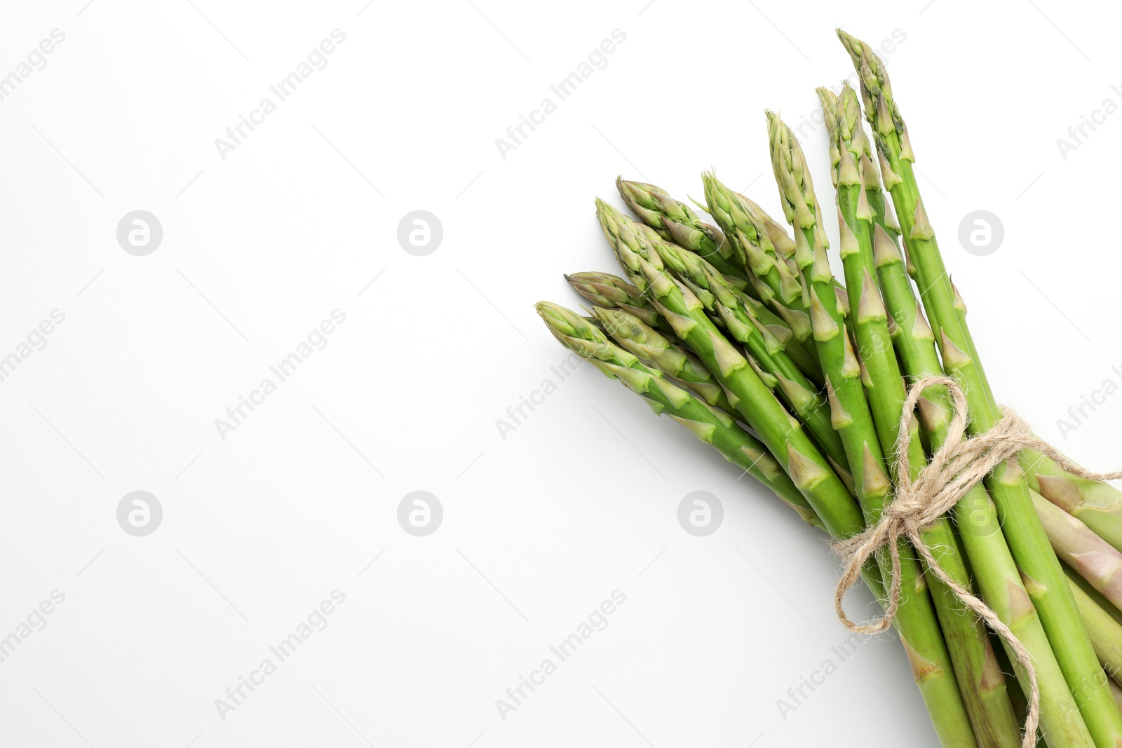 Photo of Bunch of fresh green asparagus stems on white background, top view. Space for text