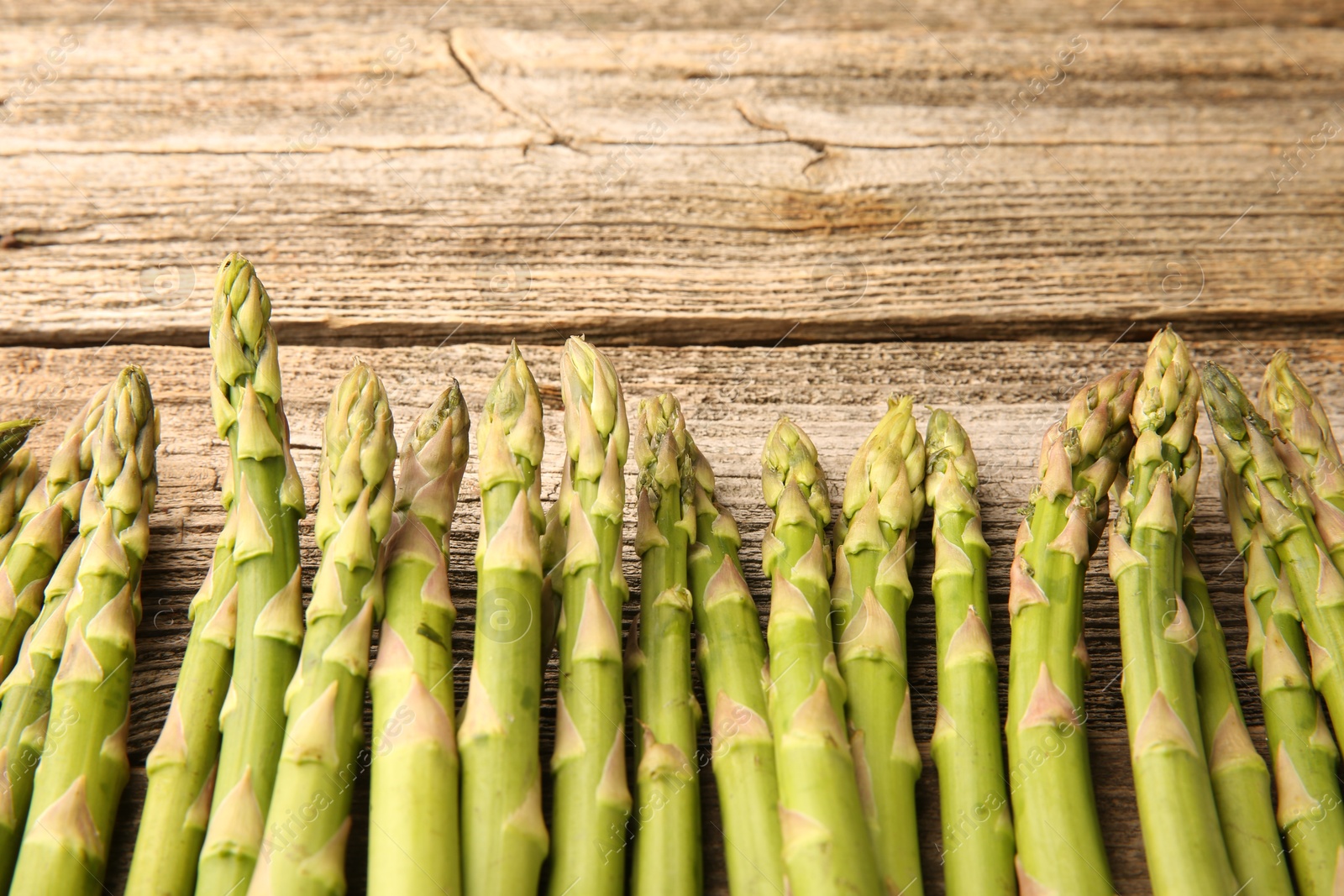 Photo of Fresh green asparagus stems on wooden table, flat lay. Space for text