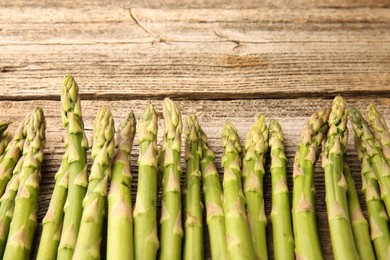 Fresh green asparagus stems on wooden table, flat lay. Space for text