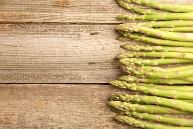 Fresh green asparagus stems on wooden table, flat lay. Space for text