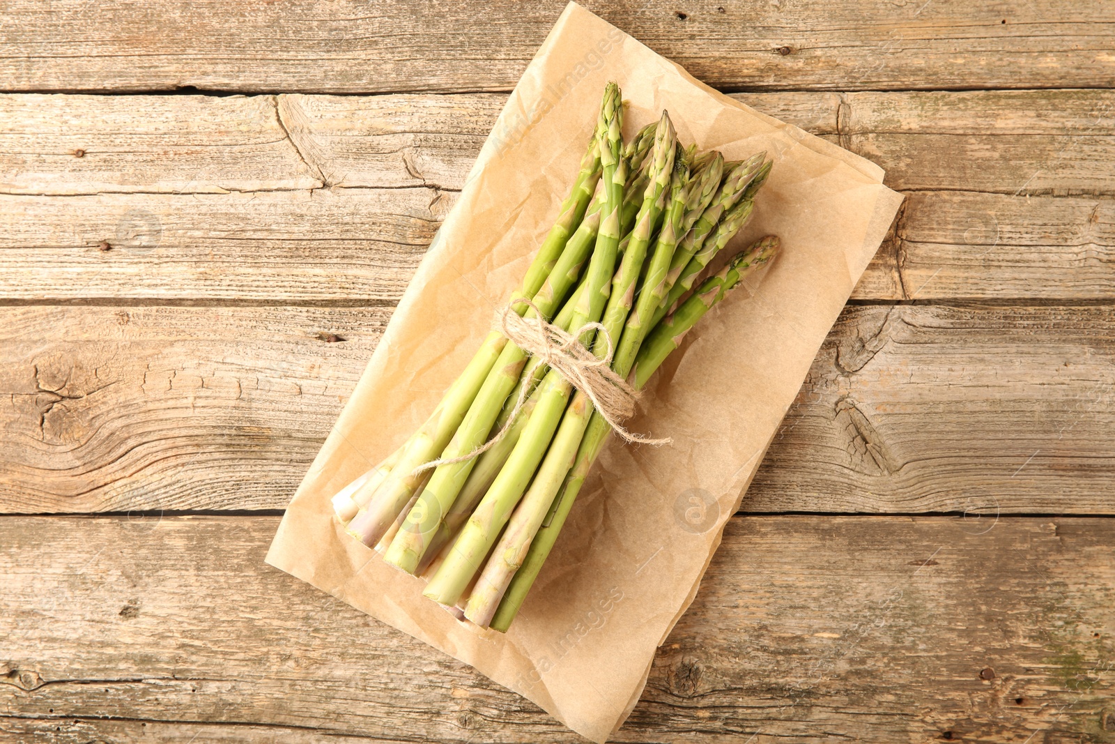 Photo of Bunch of fresh green asparagus stems on wooden table, top view