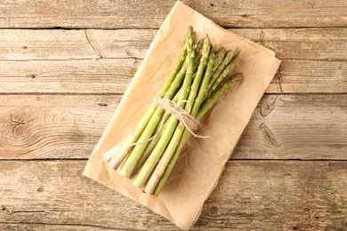 Bunch of fresh green asparagus stems on wooden table, top view