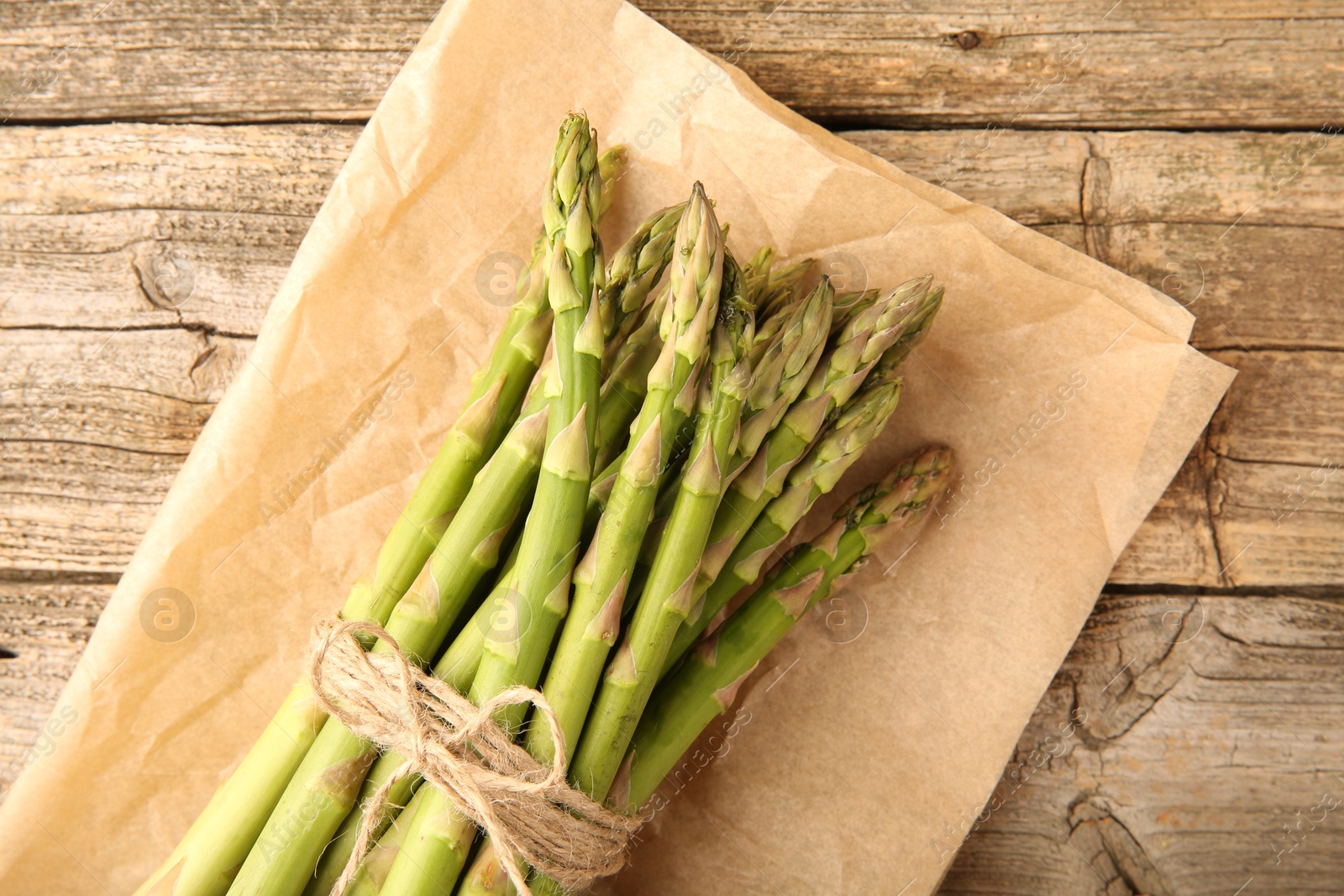 Photo of Bunch of fresh green asparagus stems on wooden table, top view